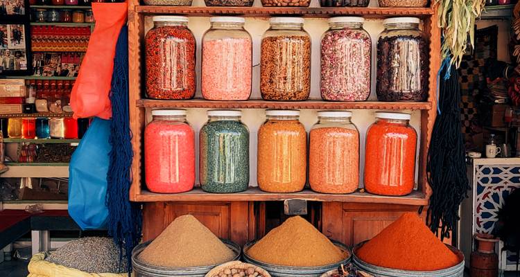 Frascos coloridos de especias y pirámides ordenadas de condimentos en polvo exhibidos en un puesto de zoco marroquí.