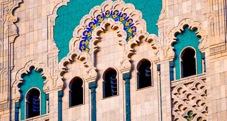 Primer plano de arcos moriscos ornamentados con incrustaciones de azulejos turquesa en la fachada de la Mezquita Hassan II.