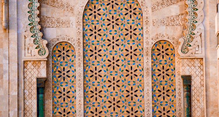 Entrada de piedra detallada con patrones de mosaico floral en el exterior de la Mezquita Hassan II.