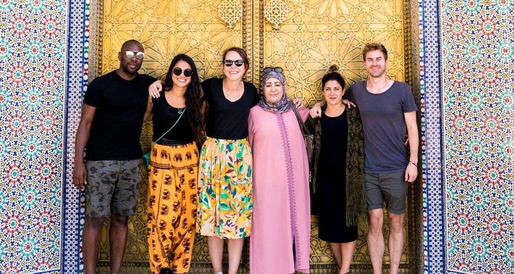Group of tourists posing in front of ornate doors.