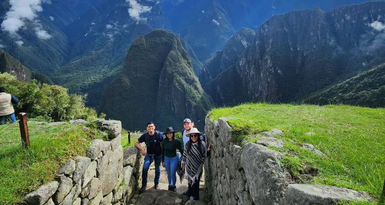 Un groupe de personnes debout sur des terrasses incas avec des montagnes en arrière-plan.