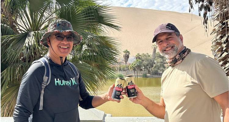 Deux hommes trinquant avec des canettes près d'une oasis du désert.