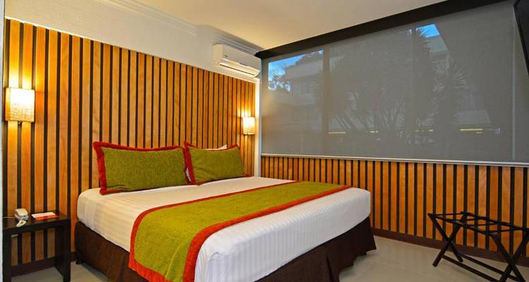 Une chambre d'hôtel douillette avec un lit confortable, décorée de couleurs chaudes.