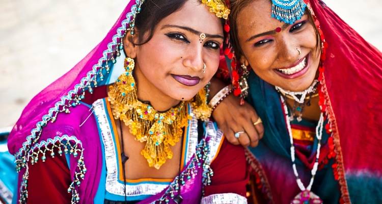 Two women in traditional vibrant dresses, smiling.