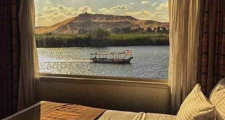 Vue depuis une fenêtre d'un bateau sur une rivière avec des collines.