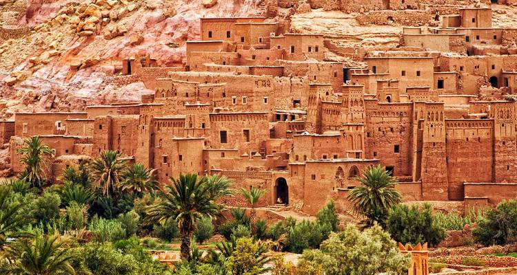Pueblo fortificado de tierra de Ait Benhaddou construido en la ladera con palmeral en primer plano