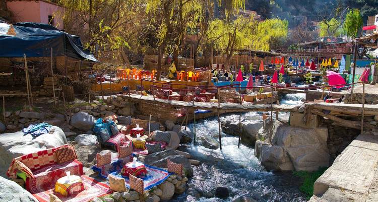 Cafés coloridos al aire libre junto al río con alfombras y cojines al lado del arroyo de montaña en el Valle de Ourika