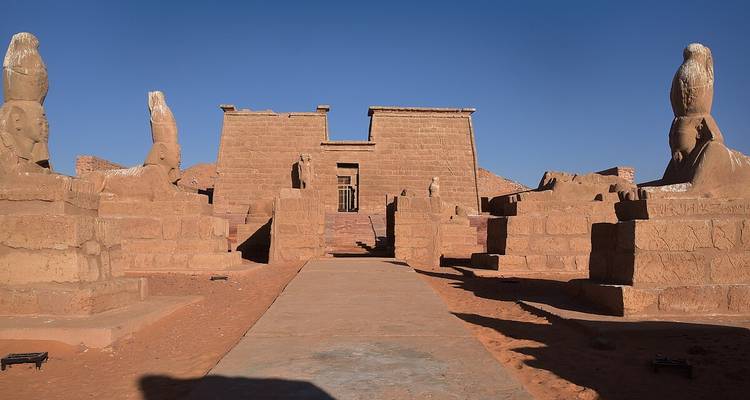 Temple structure with statues in the desert.