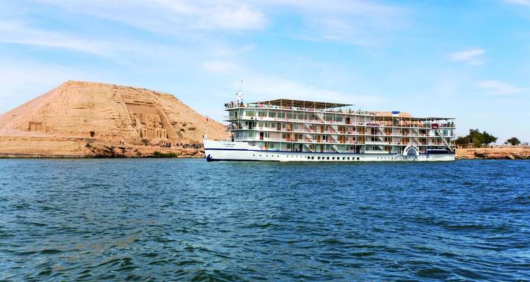 Cruise ship sailing near an ancient temple structure.