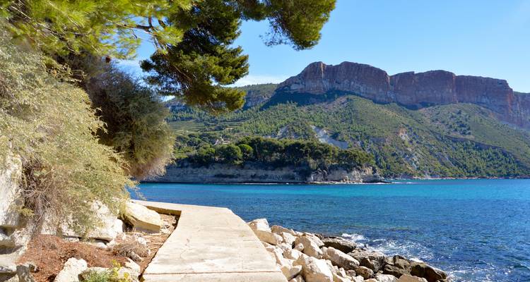 Path along a rocky coastline with clear blue water in Cassis.