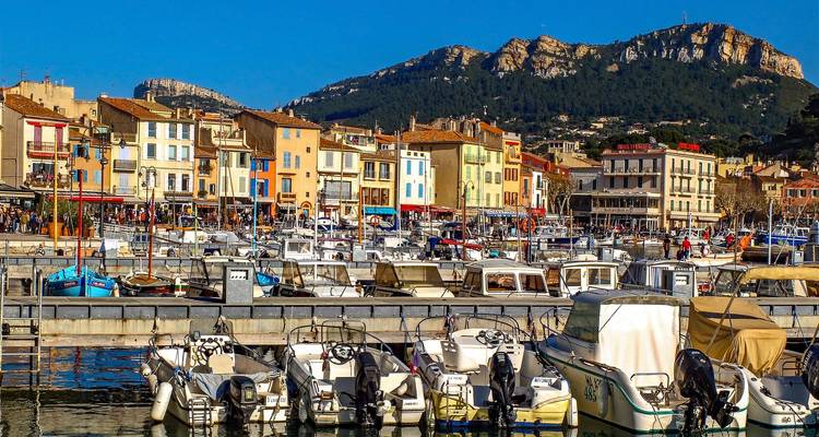 Harbor scene with boats docked and colorful buildings in the background under clear blue skies.