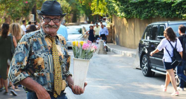 Homme tenant un panier de fleurs dans une scène de rue.