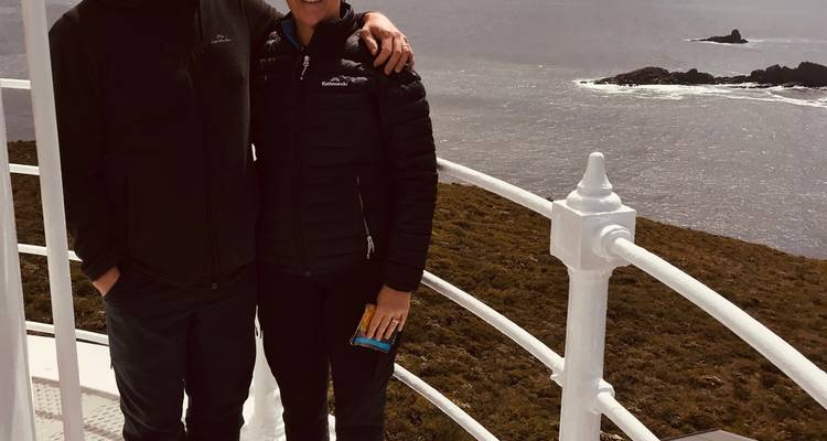 Couple standing on a lighthouse with ocean view in the background.