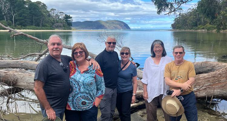 Group of people posing near a lake with distant hills.