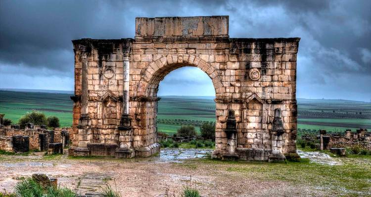 An ancient stone archway with dramatic skies.