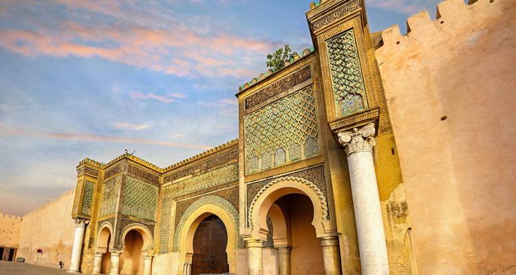 An ornate gate with colorful tile patterns under a vibrant sky.