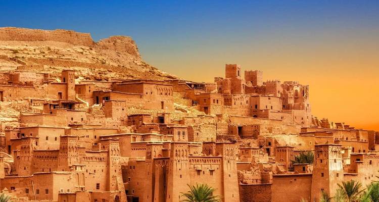 Ancient fortified village with ochre-colored buildings at sunset.