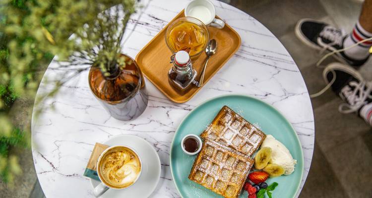 A table set with waffles, coffee, and juice.