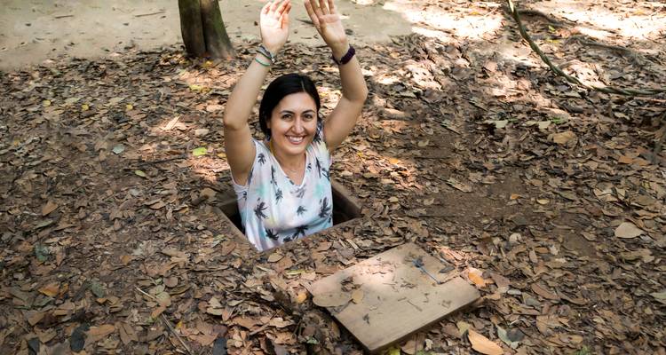 Woman emerging from a small tunnel in a forest.