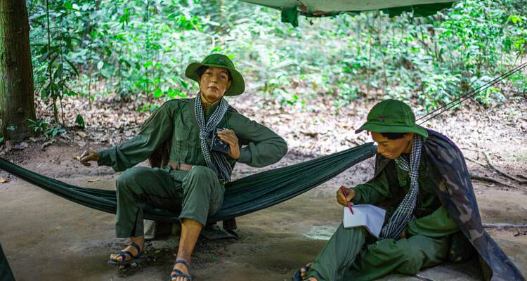 Two mannequins dressed as soldiers are seated, interacting in a forest.