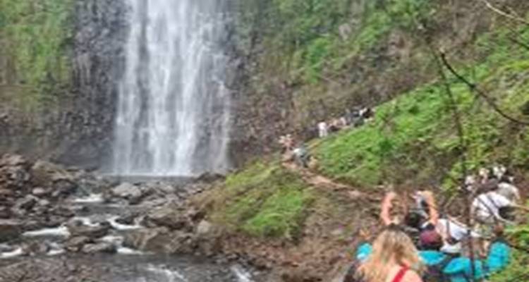 Touristen, die auf einem Weg zu einem Wasserfall gehen.