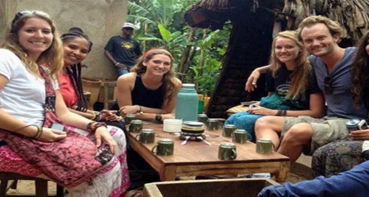 Gruppe von Menschen, die um einen Tisch mit Tassen sitzen.