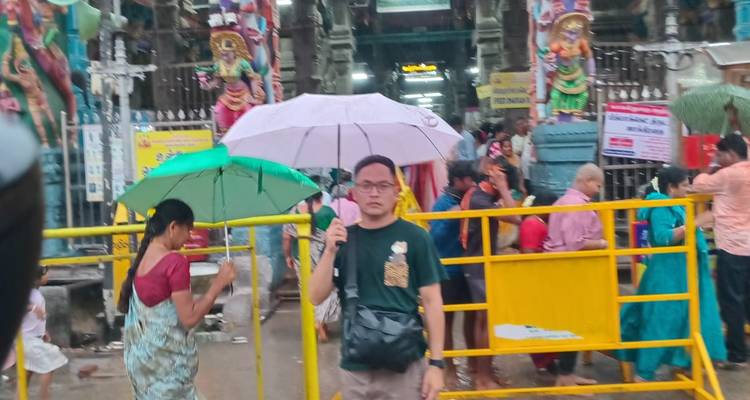 Imagen borrosa de una persona parada con un paraguas entre las puertas del templo.