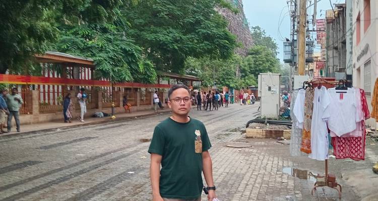 Una persona parada en una calle empedrada con árboles y edificios al fondo.