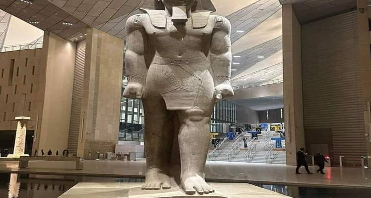 Groot oud standbeeld in een modern gebouw.