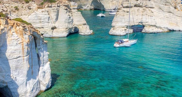Les eaux turquoise de la mer Égée entourant des falaises blanches spectaculaires et des arches naturelles à Kleftiko avec des voiliers ancrés dans la crique.