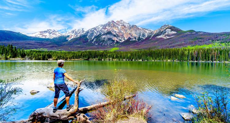 Excursionista de pie junto a un lago con vista a la montaña en el Parque Nacional Jasper.