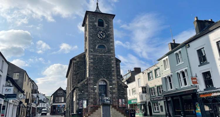 La tour de l'horloge historique s'élevant au-dessus d'une rue pittoresque de boutiques sous un ciel bleu éclatant à Keswick.