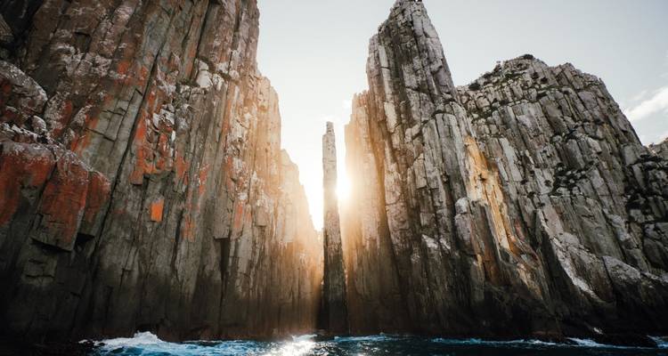 Sun peeking through narrow cliffs by the sea.