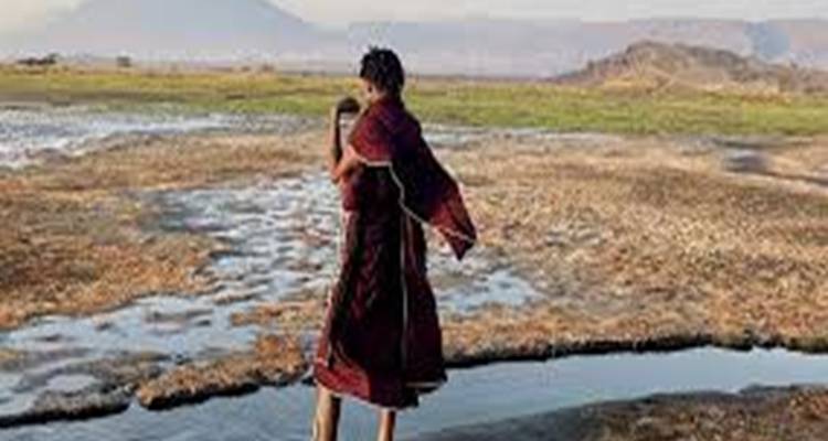 Persoon die loopt op een vlakte met bergen in de verte.