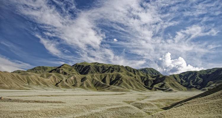 Paysage vallonné avec une végétation clairsemée sous un ciel nuageux.