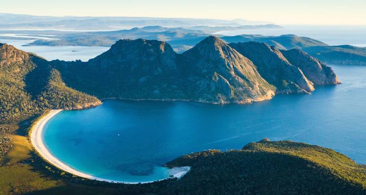 Schilderachtig uitzicht op Wineglass Bay met blauwe wateren en omliggende bergen.