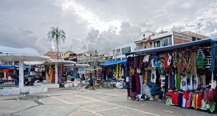 Buitenmarkt met kramen die kleurrijke textiel en kleding verkopen.