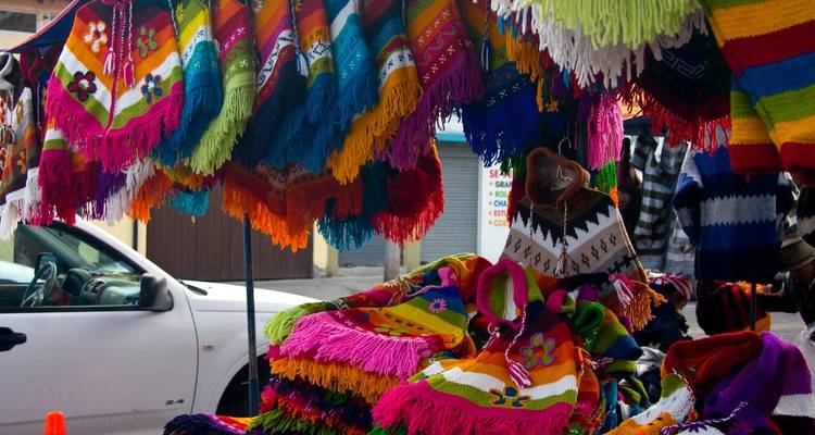 Kleurrijke poncho's en textiel uitgestald in een marktkraam.