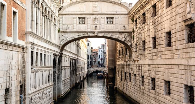The famous Bridge of Sighs arching over a narrow canal lined with historic stone buildings in Venice.