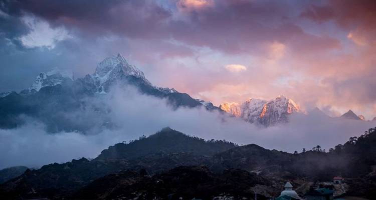 Pics de montagne brumeux au lever du soleil avec un ciel coloré.