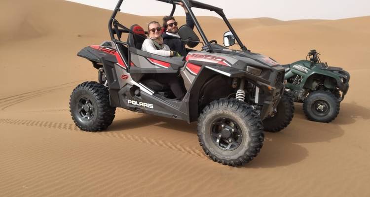 Dos personas en un buggy de dunas en un paisaje desértico.