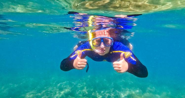 Personne faisant de la plongée avec tuba qui fait un signe de pouce levé sous l'eau.