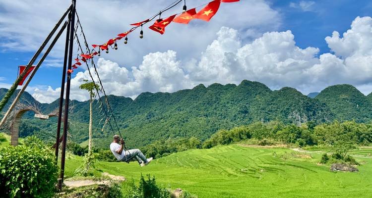 Personne se balançant avec des rizières et des montagnes en arrière-plan.