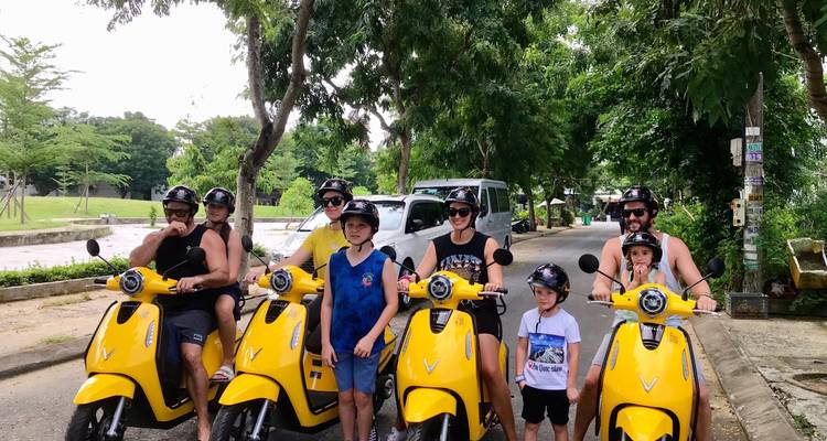 Groupe de personnes sur des scooters jaunes posant pour une photo dans la rue.