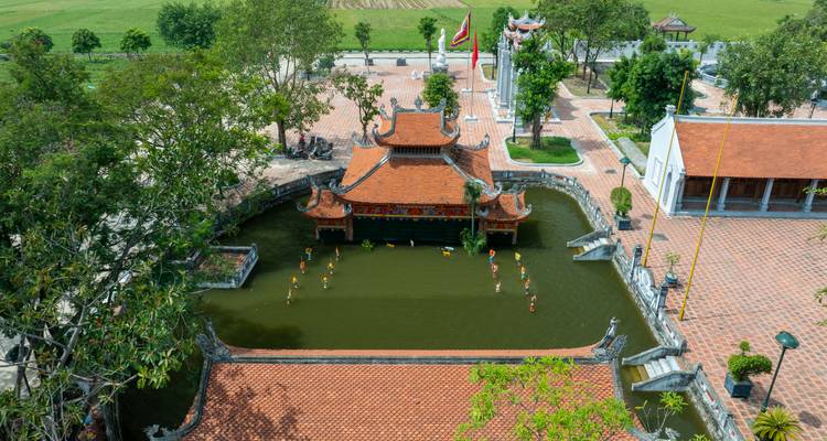 Vue aérienne de bâtiments de temple avec des toits en brique et un étang.