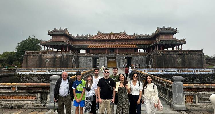 Grupo de personas frente a una gran estructura tradicional vietnamita.