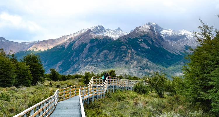 Passerelle en bois menant à une chaîne de montagnes.