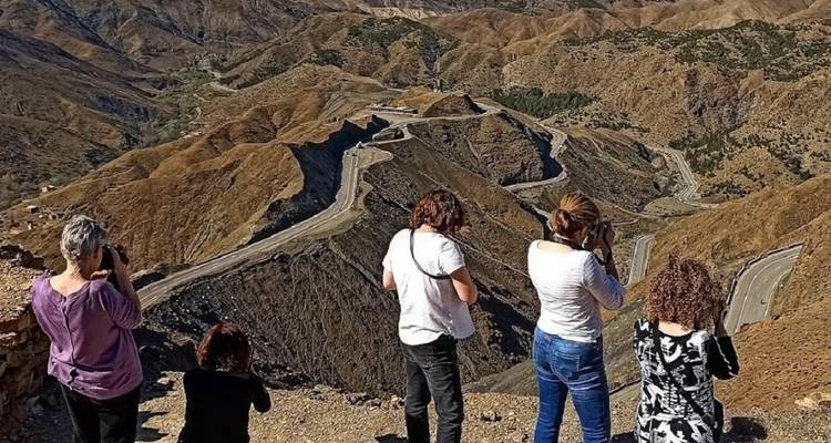 Groupe de personnes prenant des photos d'une route de montagne sinueuse.