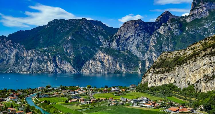 Panoramic view of a lake surrounded by mountains and greenery.