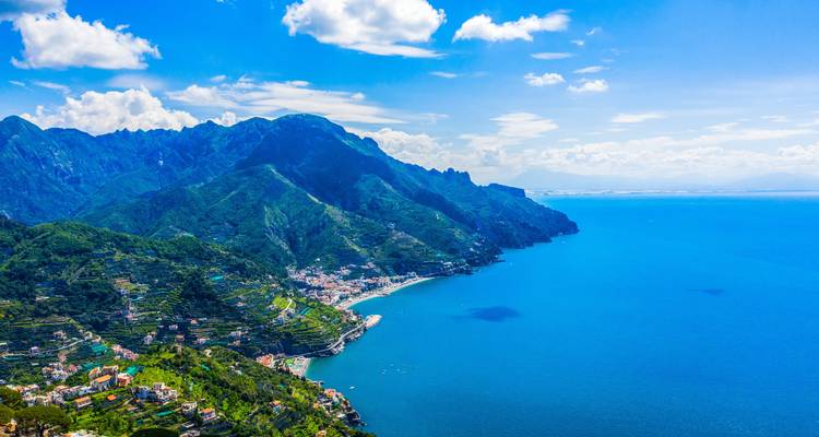 Vista aérea de la Costa Amalfitana con montañas exuberantes y mar azul.